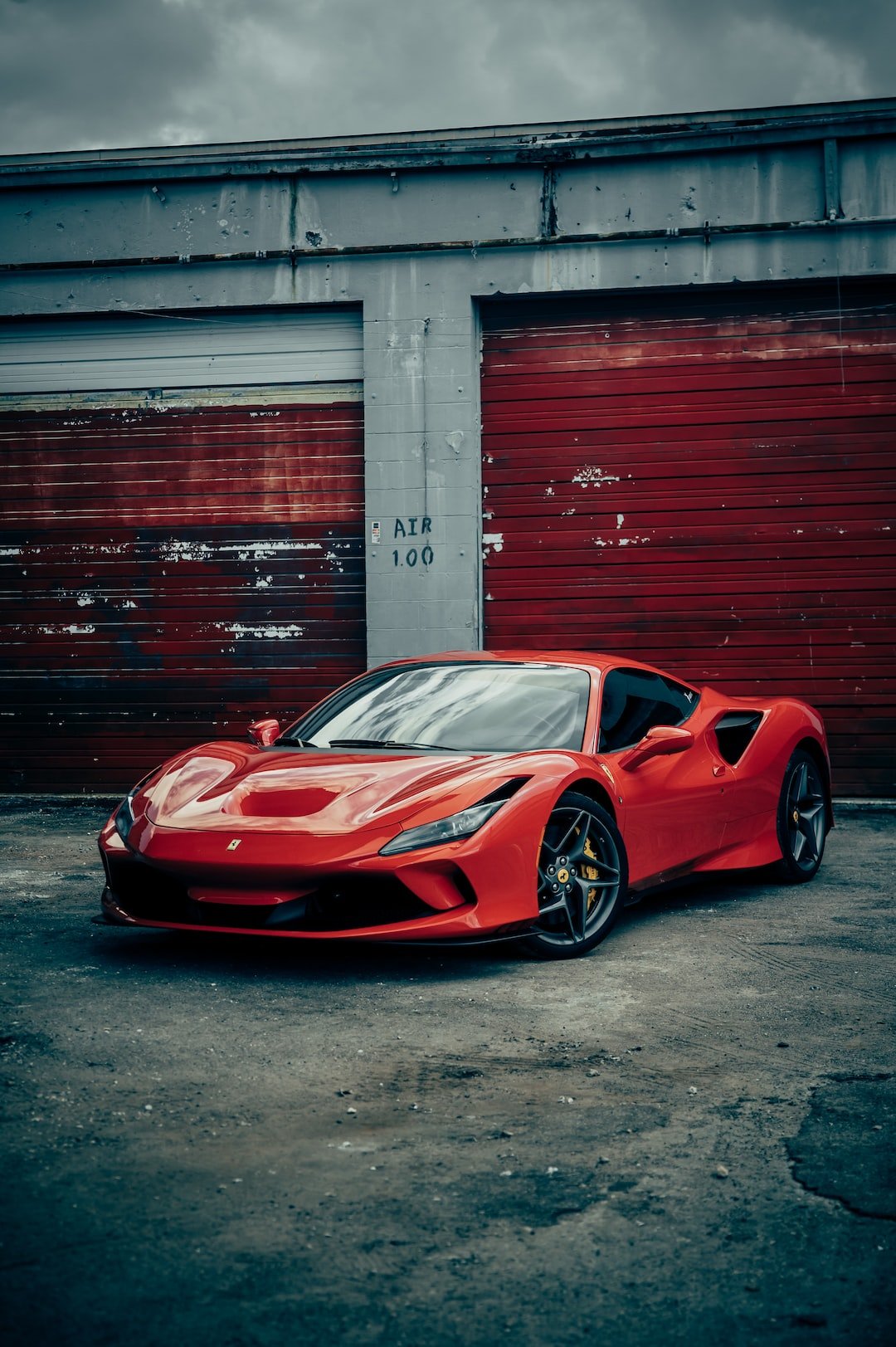red ferrari 458 italia parked beside red wall